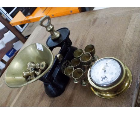 A set of kitchen scales with brass weights, six brass egg cups and a ship's barometer 