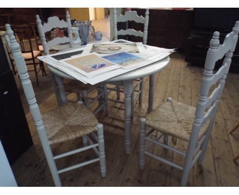 A circular grey painted kitchen or patio table together with four matching ladder back style chairs with rush seats 