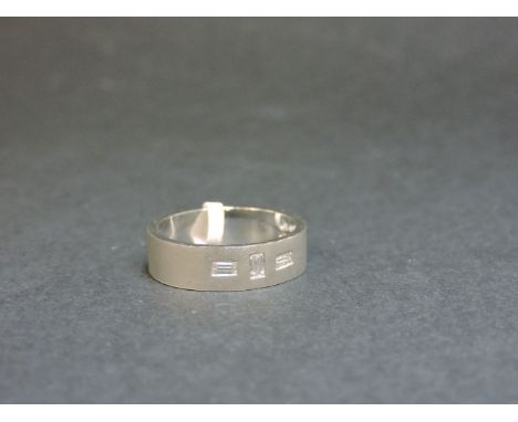 An 18ct white gold flat section wedding ring, with three baguette cut diamonds gypsy set to a sand blast ground