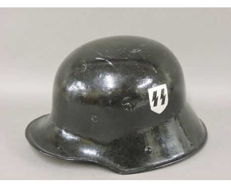A World War II German steel helmet, now black with 'SS' insignia, the inner lined with leather
