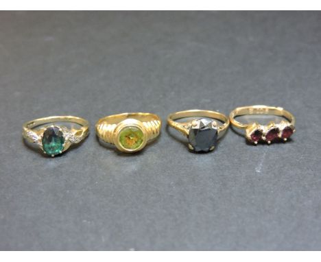 A haematite ring, marked 9ct, a 9ct gold three stone garnet ring, a peridot ring tested as approximately 18ct gold, and a 9ct