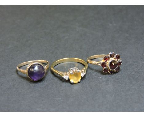 A 9ct gold citrine and diamond three stone ring, a single stone cabochon amethyst ring tested as approximately 9ct gold, and 