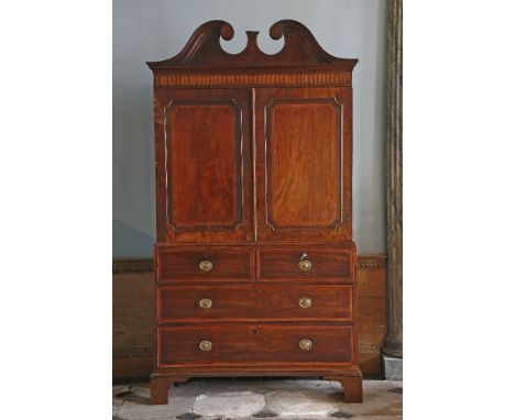 A George III mahogany linen press,with a swan neck pediment over an inlaid geometric frieze and two cupboard doors with re-en