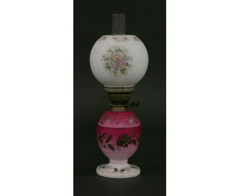 A Victorian glass oil lamp,the red and white base with painted decoration, with lift-out reservoir and white globe shade deco