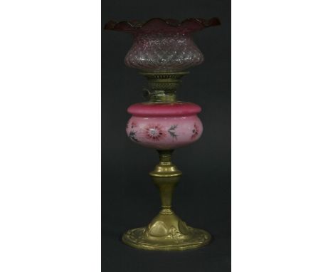 An Art Nouveau brass oil lamp,with pink glass reservoir, Linden duplex burner and moulded cranberry shade with wide wavy edge