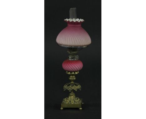 A small Victorian brass candlestick oil lamp,the base with moulded decoration and leafy branches, swirl moulded pink reservoi