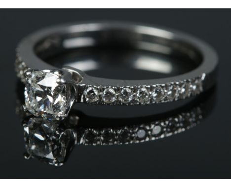 A Tiffany &amp; Co Harmony platinum and diamond ring. The brilliant cut centre stone in claw setting flanked by eight smaller