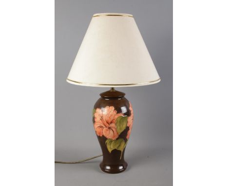 A Moorcroft pottery table lamp, with brown glaze decorated in the hibiscus pattern. Height: 61cm.  