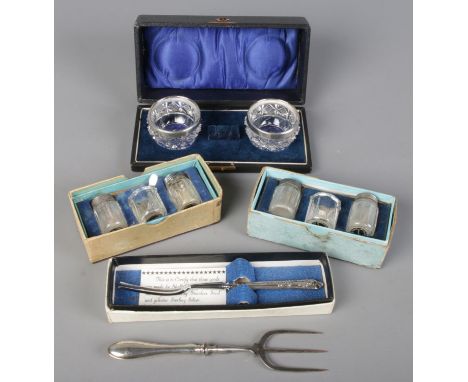 Two boxed salt and pepper pots with silver lids along with a pair of silver rimmed salts and silver handled knife and fork.  