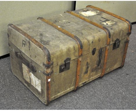 A vintage wooden and canvas bound travelling steamer trunk, 45cm high x 81cm wide x 52cm deep, having railway labels to the e