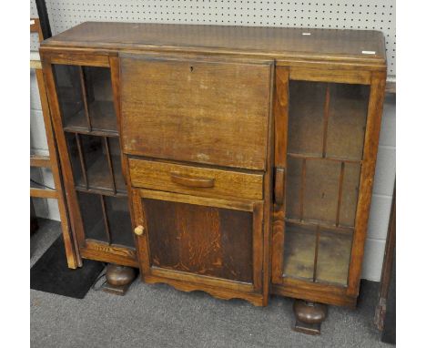 A vintage oak art deco mid century drinks cabinet with two glazed doors, drop front above a single drawer and cupboard,122cm 