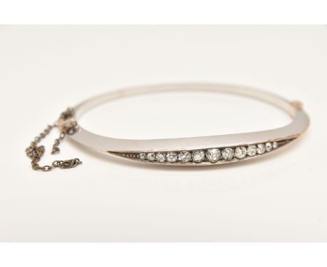 A DIAMOND SET HINGED BANGLE, rhodium plated, set with a row of graduating old cut diamonds, estimated total diamond weight 0.