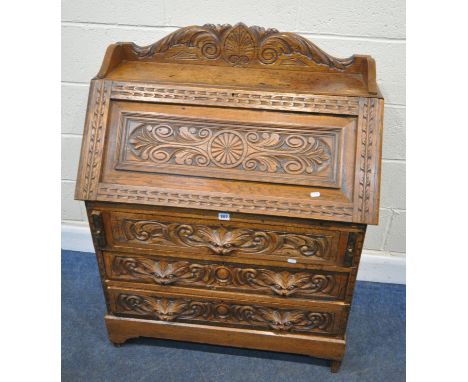 A 20TH CENTURY CARVED OAK GREEN MAN BUREAU, with raised back and sides, the fall front door enclosing a fitted interior, over