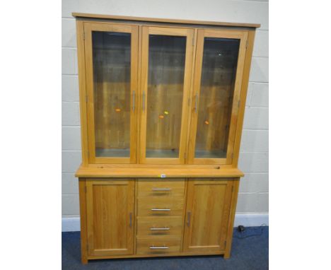 A MODERN LIGHT OAK WALL CABINET, fitted with three glass doors, that are enclosing an arrangement of glass shelves, on a base