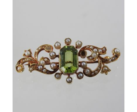 An early 20th century unmarked peridot and pearl brooch, of scrolled design, boxed