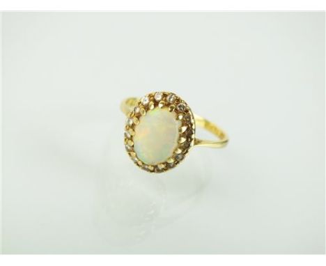 An 18ct gold opal and diamond cluster ring, designed as a central oval cabochon opal claw set within a border of eight cut di