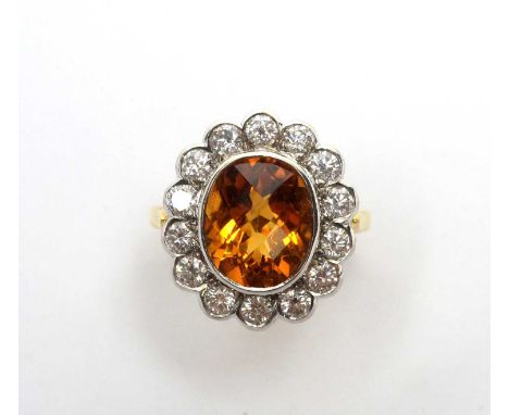 A citrine and diamond cluster ring, the oval fancy-cut citrine collet set surrounded by fourteen brilliant cut diamonds weigh