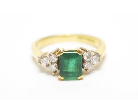 An emerald and diamond ring, the canted square step-cut emerald flanked by six brilliant cut diamonds, on 18ct yellow gold sh