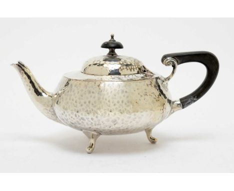 An Arts &amp; Crafts silver teapot, by Charles Edwards, London 1913, of circular form with hammered finish, shaped ebonised h