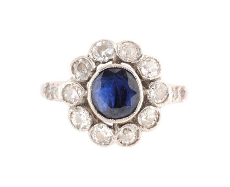A sapphire and diamond cluster ring, the circular facet cut sapphire collet set surrounded by ten old cut diamonds flanked by