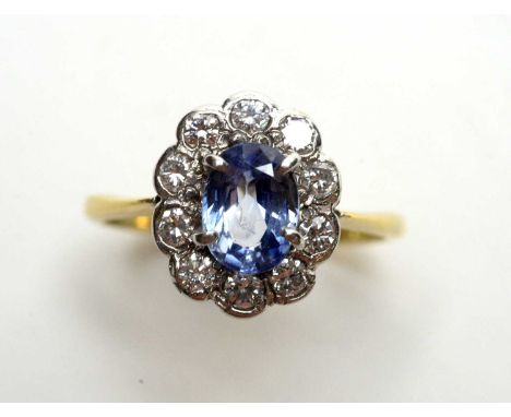 A sapphire and diamond cluster ring, the oval facet cut sapphire surrounded by ten brilliant cut diamonds, on 18ct yellow gol