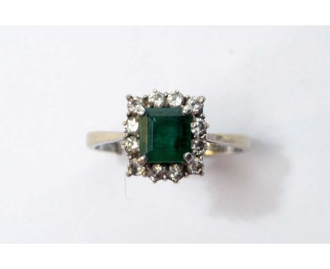 An emerald and diamond ring, the rectangular step-cut emerald surrounded by twelve brilliant cut diamonds weighing a total of