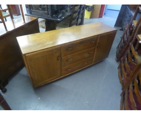 ERCOL LIGHT ELM SIDEBOARD WITH CENTRAL NEST OF THREE DRAWERS, FLANKED BY CUPBOARDS ALL WITH RECESSED KNOB HANDLES 