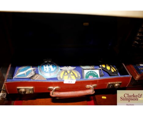 A leather case and contents of various vintage car badges 