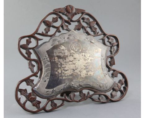 A mid 20th century Chinese white metal presentation plaque mounted on a pierced hardwood easel frame, the engraved inscriptio
