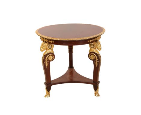 An Empire style gilt metal mounted mahogany centre table, the circular top with swag cast edge, raised on three rams head cap