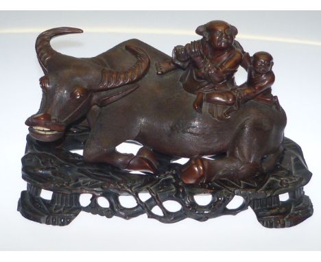 A good Chinese hardwood carving of a water buffalo, 19th Century, the large carved group depicting a man playing an ivory flu