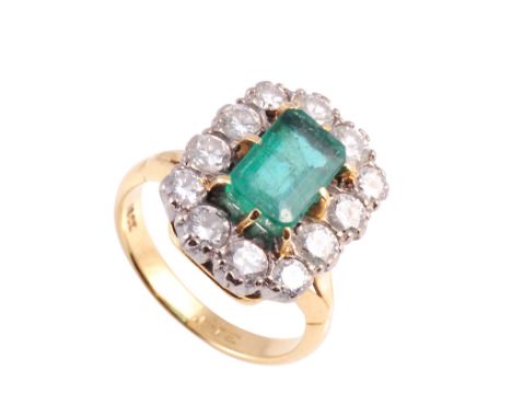 An emerald and diamond ring, the rectangular cut emerald eight claw set, raised within a bezel of twelve slightly graduating 