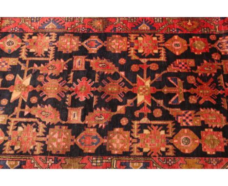 A Malayer runner, with a repeating pattern against a blue/black ground within a pink/red border. 500cm by 104cm