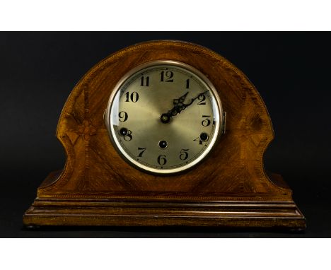 An Early 20th Century Mantle Clock In wood casing, of typical form with chevron inlay, brushed gold dial and brass surround.