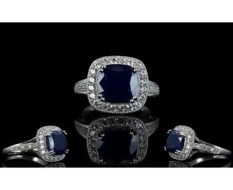 Sapphire and Natural White Zircon Ring, with ruby accents; a 6.5ct cushion cut blue sapphire framed with round cut, natural w