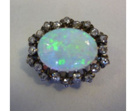 A yellow metal brooch, set with a central opal, surrounded by twenty diamonds