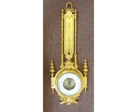 A late 19thC gilt brass barometer, ornately cast with garlands, mask motifs and reeded pillars, set with a thermometer and a 