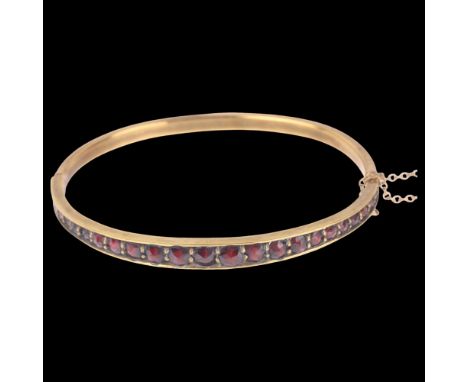 A Bohemian garnet hinged bangle, gilt-metal settings with graduated round faceted garnets, setting height 5.8mm, internal cir