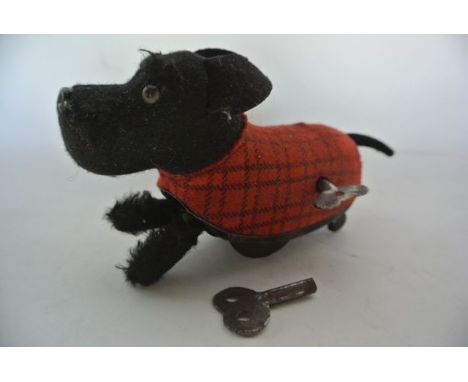 A small vintage clockwork dog depicted wearing a tartan jacket, stamped to underside Schuco-Patent-Foreign
