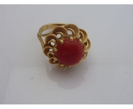 A coral ring, the open-worked floral border centred with a round coral, rope-twist shoulders, in 18ct gold, size P 1/2