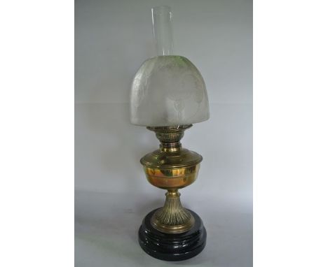 A brass oil lamp set upon a cylindrical ebonised base, the burner marked Matadorbrenner accommodating a clear glass chimney a