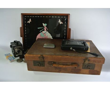 A vintage stitched leather suitcase containing a Conway camera, a Kodak EK8 instant camera, a machine decorated cigarette cas