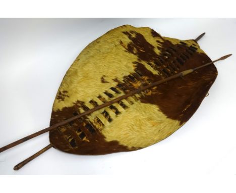 An African cow hide shield and a hunting spear, length of shield approx 135cm.