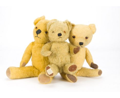 Three post-war British teddy bears: a Chiltern Hugmee with golden mohair/mix plush, orange and black glass eyes and oil cloth