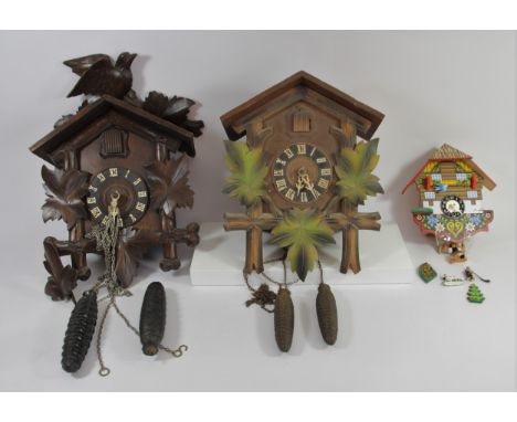 Two black forest cuckoo clocks together with a German made novelty wall clock in the form of a Swiss chalet.  (3) 