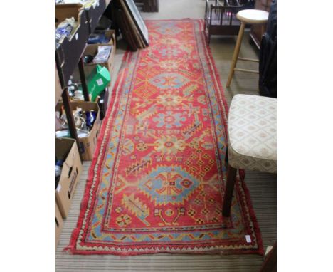A RED GROUND WOVEN WOOLLEN FLOOR RUNNER 