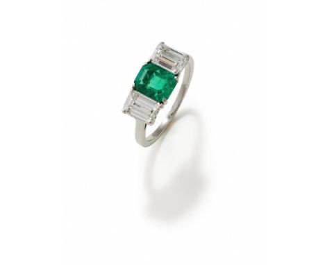 AN EMERALD AND DIAMOND THREE STONE RING The rectangular step cut emerald with canted corners, between similarly cut diamond s