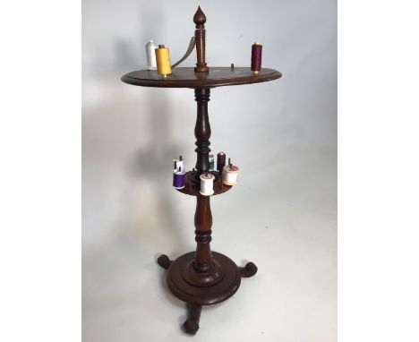 A circular mahogany sewing table with turned spindle reel stands on circular plinth tripod base. W:40cm x D:40cm x H:85cm