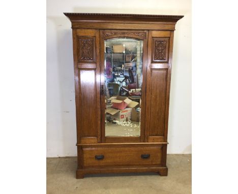 An art nouveau style early 20th century oak wardrobe with bevelled mirror door with interior brass hangings, base with large 