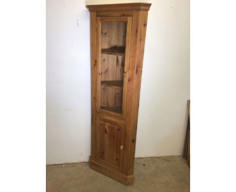 A modern pine corner cupboard with glazed door to two shaped shelves with lower cupboard also with an interior shaped shelf. 